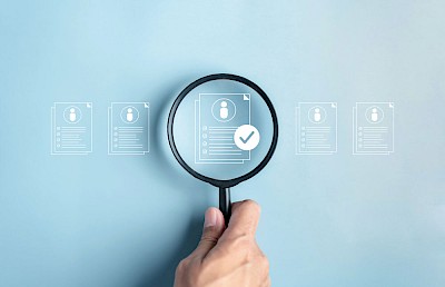 Magnifying glass enlarging an illustration of a checklist to illustrate the definition of Digital HR Marketing