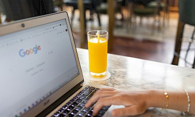 Laptop mit der Google Startseite + einem O-Saft