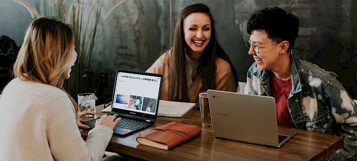 Lachende Kollegen vor Laptops zur Veranschaulichung der Social Media Blogs