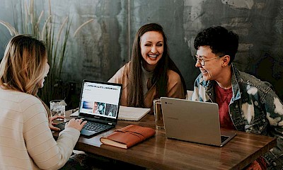 Lachende Kollegen vor Laptops zur Veranschaulichung den Social Media Blogs