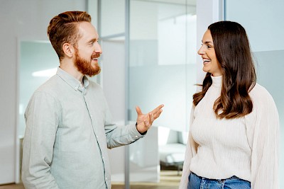 Ein Mann erklärt einer Frau attraktive Preise zur Social Media Betreuung