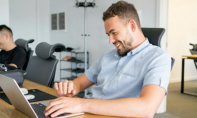 Ein Mann und eine Frau sitzen an einem Tisch und schauen auf einen Laptop