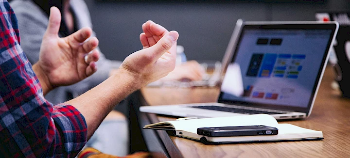 Man met laptop gebaart in vergadering