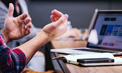 Mann mit Laptop gestikuliert im Meeting