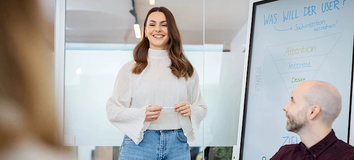 Frau erklärt Zielgruppenanalyse an Whiteboard