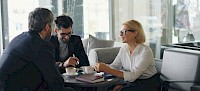 Two men and a woman are sitting at a table, chatting