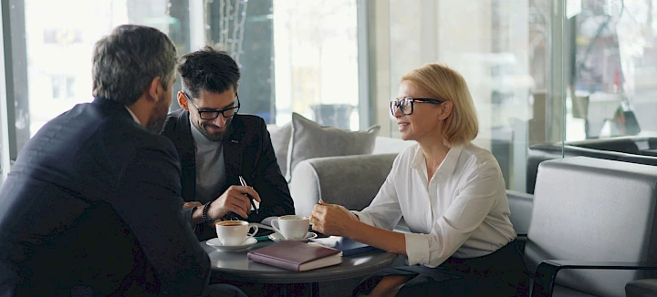 Two men and a woman are sitting at a table, chatting
