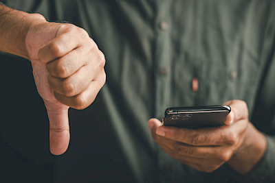A man holding a smartphone with his thumb pointing downwards