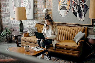 Kundin auf dem Sofa mit Laptop auf den Knien