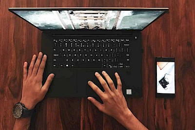 Hände auf Laptoptastatur mit Bild auf Bildschirm zur Veranschaulichung von Bilddatenbanken